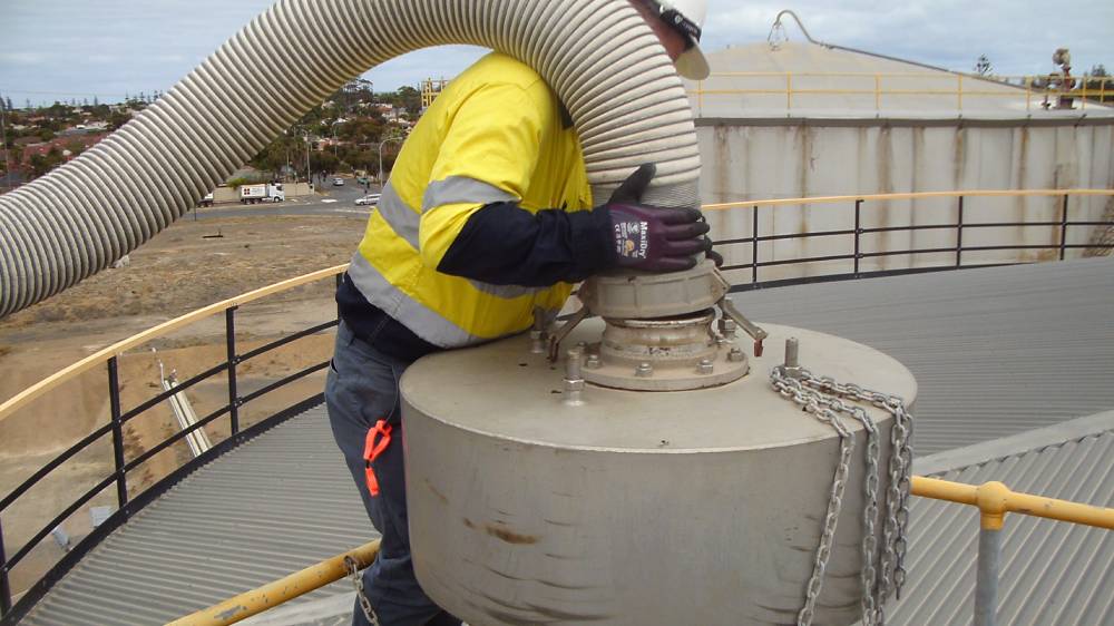 Operator undertaking removal of heavy hose at an awkward height to inspect tank vents for blockages.